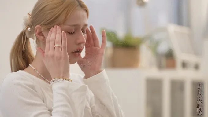 A stressed woman pressing her fingertips to her temples